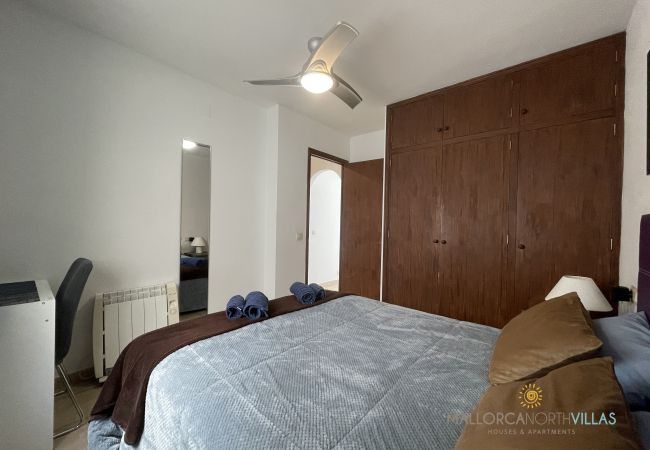 Master bedroom with double bed and built-in wardrobe Bedroom with a double bed dressed in blue and brown tones, wooden wardrobe, and ceiling fan.