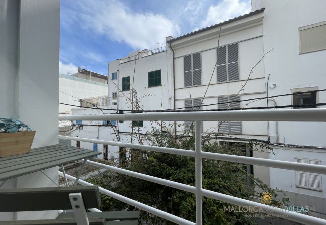 Balcony overlooking an inner courtyard Balcony with a white railing and a folding table, overlooking an inner courtyard surrounded by white buildings with shutters.