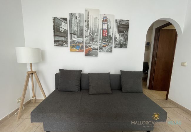Living room with sofa bed and modern New York decor Living room with dark sofa bed, New York-themed wall art, and a floor lamp in a bright space.