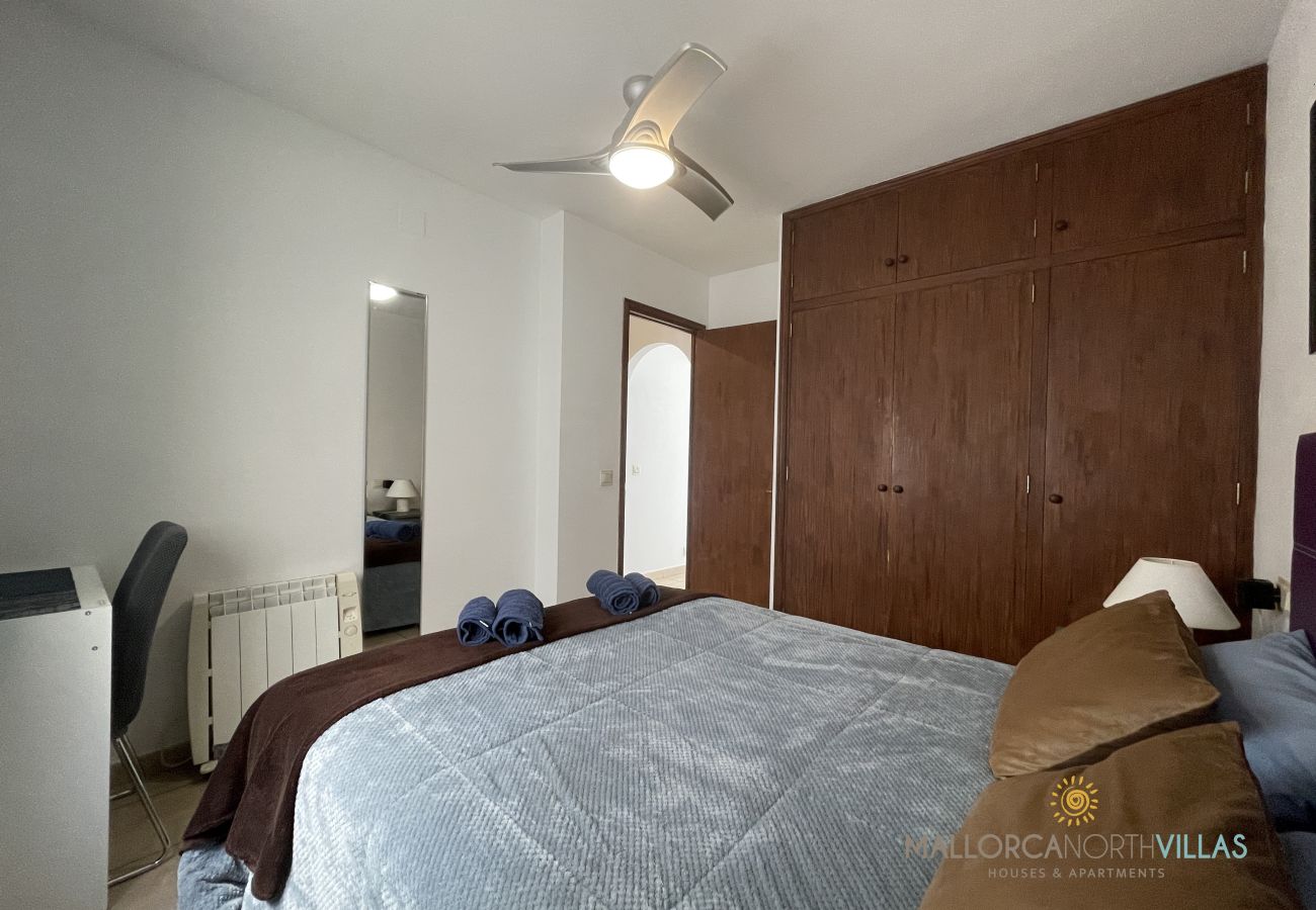 Master bedroom with double bed and built-in wardrobe Bedroom with a double bed dressed in blue and brown tones, wooden wardrobe, and ceiling fan.