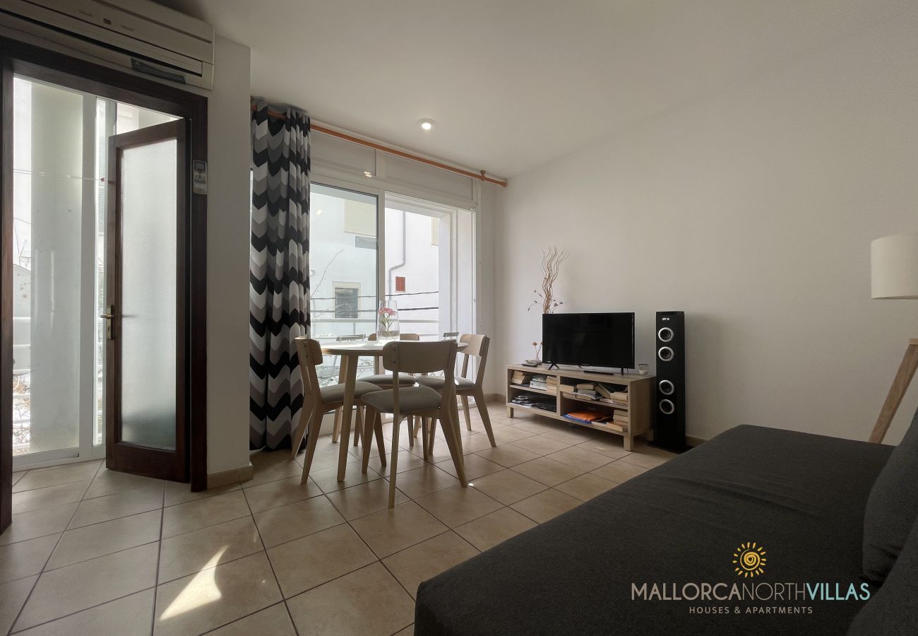 Living-dining room with balcony and TV area Living-dining room with table, chairs, sofa, air conditioning, and natural light balcony access.