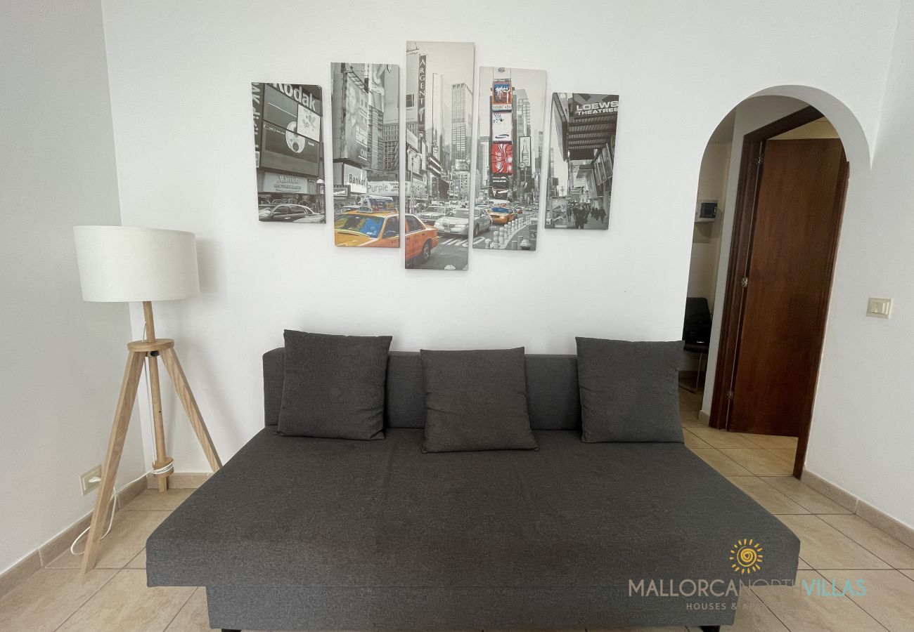 Living room with sofa bed and modern New York decor Living room with dark sofa bed, New York-themed wall art, and a floor lamp in a bright space.